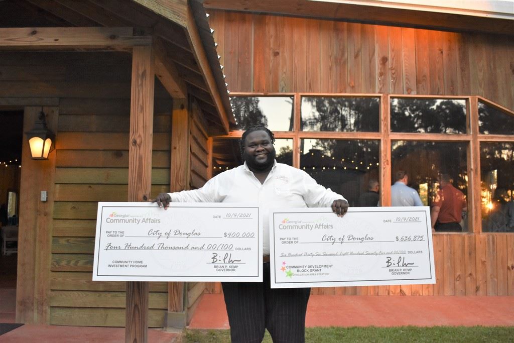 Photo of Commissioner Durham poses with large presentation checks at SGRC reception